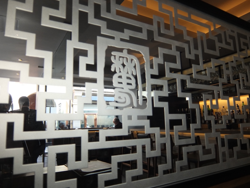A view of the dim sum bar through lattice work decorated with the "Demon Chef's" emblem